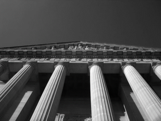 Grand courthouse architectural detail, showcasing tall columns and ornate pediment against a clear sky. Highlights judicial significance.